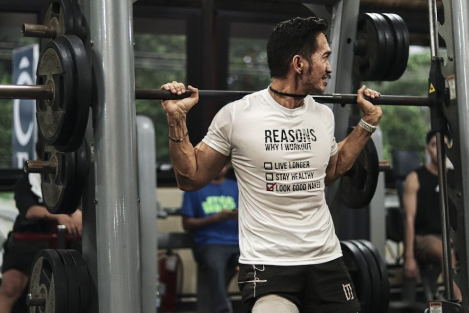 A man with a barbell squats in a gym